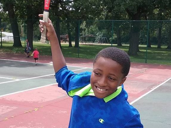 child having fun playing tennis during summer camp
